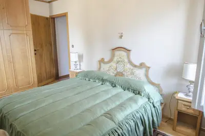 a bedroom with a bed with a green comforter at Casa Ronco in Cortina dʼAmpezzo