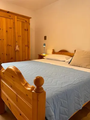 a bedroom with a wooden bed with a blue comforter at Apartment Fiemme Valley in Carano