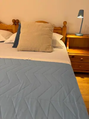 a bed with a blue quilt and a lamp on a night stand at Apartment Fiemme Valley in Carano