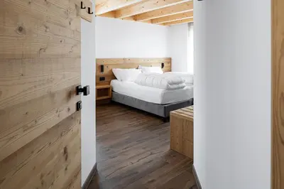 a bedroom with a bed and a wooden wall at Fiemme in Vista in Ziano di Fiemme