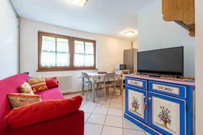 a living room with a red couch and a flat screen tv at Cesa de Sass in Mazzin