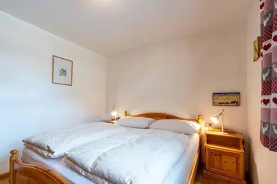 a bedroom with a large white bed with two pillows at Cesa de Sass in Mazzin