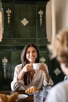 a woman sitting at a table holding a cup of coffee at Essa Suites - NEW in Caldaro