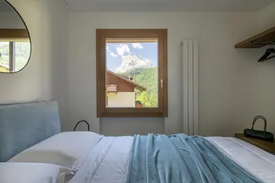 a bedroom with a bed and a window with a mountain at REMO 4 by WelcHome in San Vito di Cadore