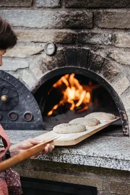 a woman is cooking bread in a brick oven at Farm apartment I neni in Lovara