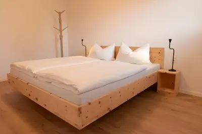 a wooden bed with white sheets and pillows at Langegger 1956 in Bolzano