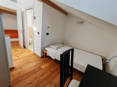 a small room with a bed and a staircase at Casanna in Cavareno
