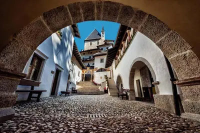an archway in a street with a castle in the background at Casanna in Cavareno