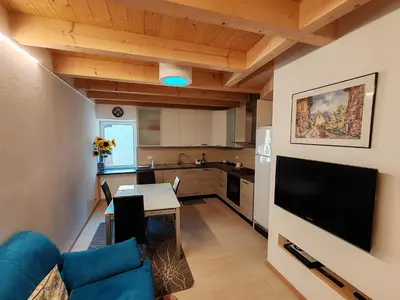 a kitchen and living room with a couch and a television at Casanna in Cavareno