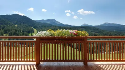 a wooden balcony with flowers on the railing at Kräuterhotel Zischghof in Obereggen