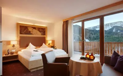 a hotel room with a bed and a balcony at Kräuterhotel Zischghof in Obereggen