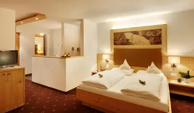 a bedroom with a large bed and a television at Kräuterhotel Zischghof in Obereggen