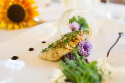 a plate of food on a table with flowers at Kräuterhotel Zischghof in Obereggen