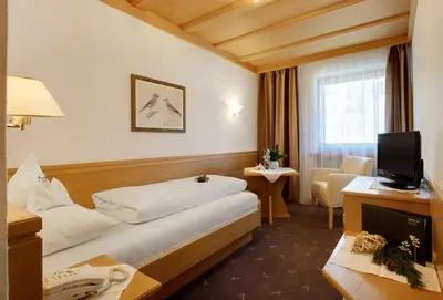 a hotel room with a bed and a television at Kräuterhotel Zischghof in Obereggen