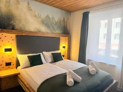 a bedroom with a large bed with slippers on it at Il bosco di Fiemme in Predazzo
