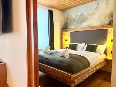 a bedroom with a bed with a painting on the wall at Il bosco di Fiemme in Predazzo