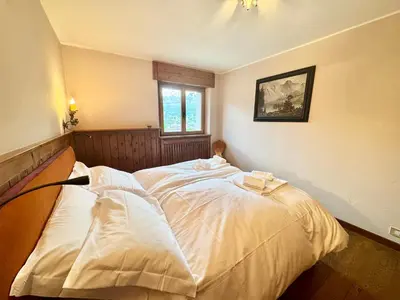 a bedroom with a white bed with a window at Villa Anna apartment - Center view - in Cortina dʼAmpezzo