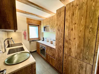 a kitchen with wooden cabinets and a sink at Villa Anna apartment - Center view - in Cortina dʼAmpezzo