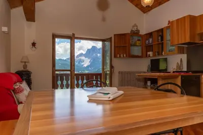 a kitchen with a wooden table and a large window at Dolomite View Loft in Colle Santa Lucia