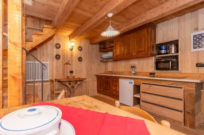 a kitchen with wooden cabinets and a table in a cabin at Tabia Sasso Bianco in Rocca Pietore