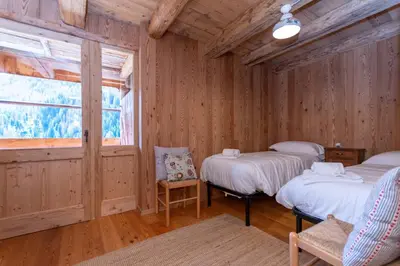two beds in a wooden room with a window at Tabia Sasso Bianco in Rocca Pietore