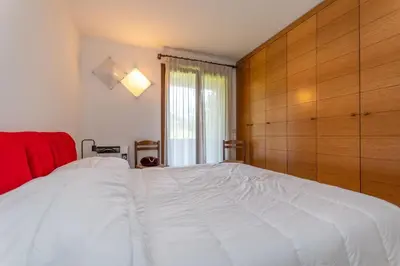 a bedroom with a large white bed with a wooden wall at Casa dei Gigli in Selva di Cadore