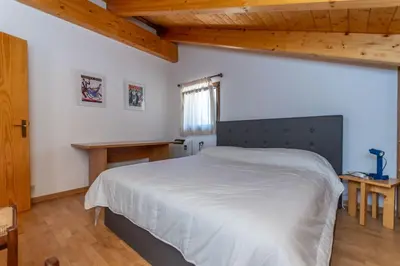 a bedroom with a white bed and a wooden ceiling at Casa dei Gigli in Selva di Cadore