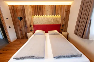 two beds in a room with wooden walls at Biohof Oberwerkstatt HAIDI in Obereggen
