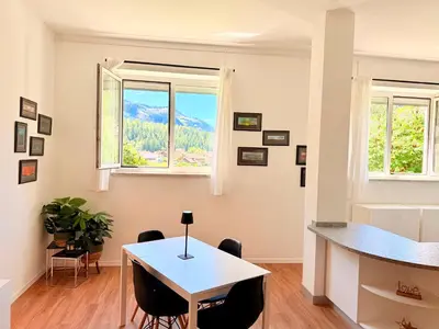 a dining room with a table and chairs and two windows at Alberi di Fiemme in Castello di Fiemme