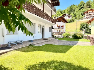a courtyard of a house with a bench and grass at Alberi di Fiemme in Castello di Fiemme