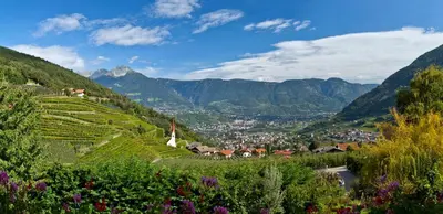 a village on a hill with mountains in the background at Apartments Gasserhof in Lagundo