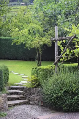 a wooden cross in a garden with a stone path at Apartments Gasserhof in Lagundo