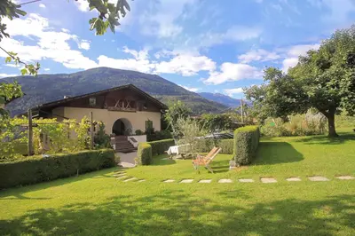 a garden with a house and a chair in the yard at Apartments Gasserhof in Lagundo