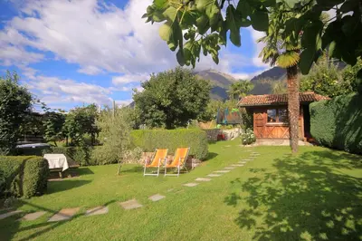 a yard with two chairs and a house with mountains at Apartments Gasserhof in Lagundo