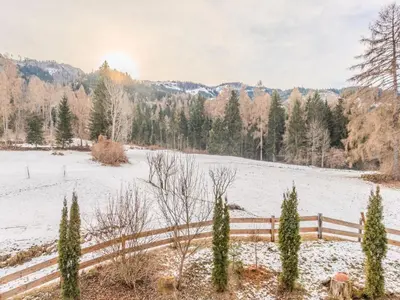 a snow covered field with a fence and trees at Chalet Altavista by Interhome in Ziano di Fiemme