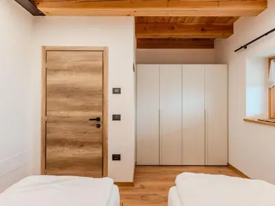 a bedroom with a door and white walls and wooden ceilings at Apartment Larice Bilocale by Interhome in Livo
