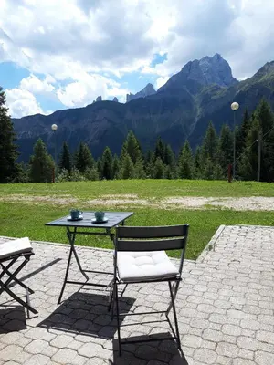 a table and chairs sitting on a patio with mountains at La Tana della Volpe, Falcade - BL in Falcade