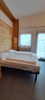 a large bed in a room with two windows at La Tana della Volpe, Falcade - BL in Falcade