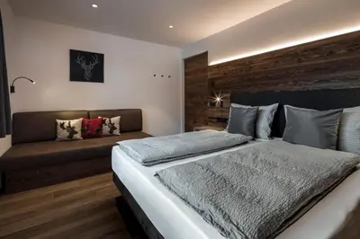 a bedroom with a large bed and a couch at Chalet Bel Plan in Ortisei