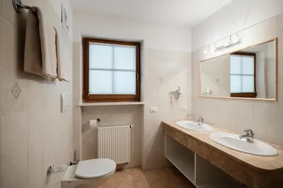a bathroom with two sinks and a toilet and a mirror at Chalet Bel Plan in Ortisei