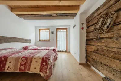 a bedroom with two beds and a wooden wall at Antico Fienile in Borca di Cadore