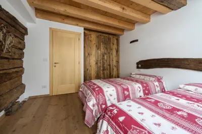 two beds in a room with wooden floors at Antico Fienile in Borca di Cadore