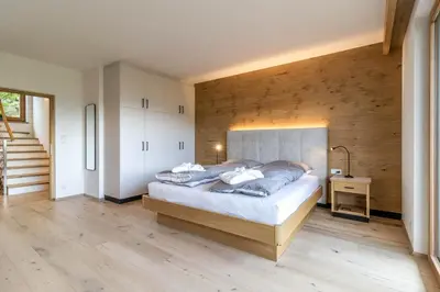 a bedroom with a large bed and a staircase at Haus Lupwald in Falzes