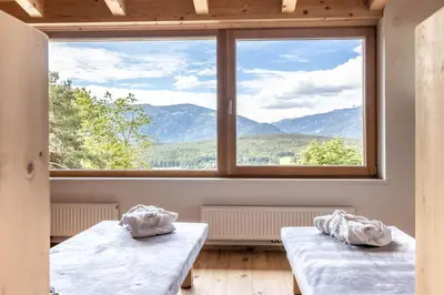 two beds in a room with a large window at Haus Lupwald in Falzes