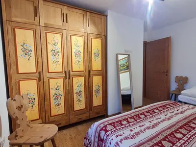 a bedroom with a bed and a large wooden cabinet at Finestra sulle Vette in Tesero