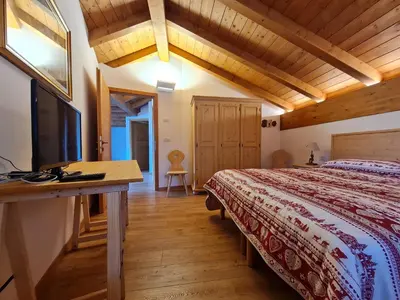 a bedroom with a bed and a desk with a television at Finestra sulle Vette in Tesero