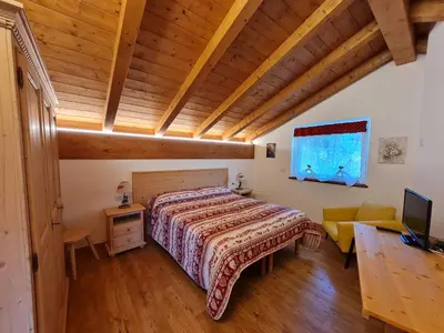 a bedroom with a bed and a desk and a television at Finestra sulle Vette in Tesero