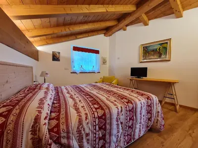a bedroom with a large bed and a desk at Finestra sulle Vette in Tesero
