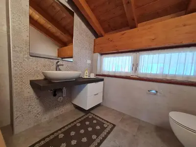 a bathroom with a sink and a toilet and a window at Finestra sulle Vette in Tesero