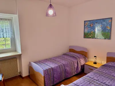a bedroom with two beds and a painting on the wall at Appartamento Olimpiadi 2026 Val di Fiemme in Panchia